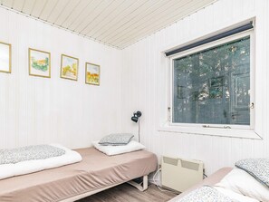 A bedroom with two beds, a window with a view of trees, and three framed pictures on the wall. - 4 Star Holiday Home in Hals (Hals)