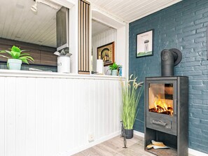 A room with a white wooden bench, a black wood-burning stove, and a blue brick wall. - 4 Star Holiday Home in Hals (Hals)