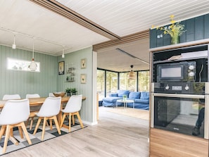A modern kitchen with built-in appliances and a dining area with a wooden table and white chairs.