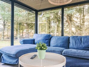 A modern living room with a blue sofa, a round table, and a potted plant. - 4 Star Holiday Home in Hals (Hals)