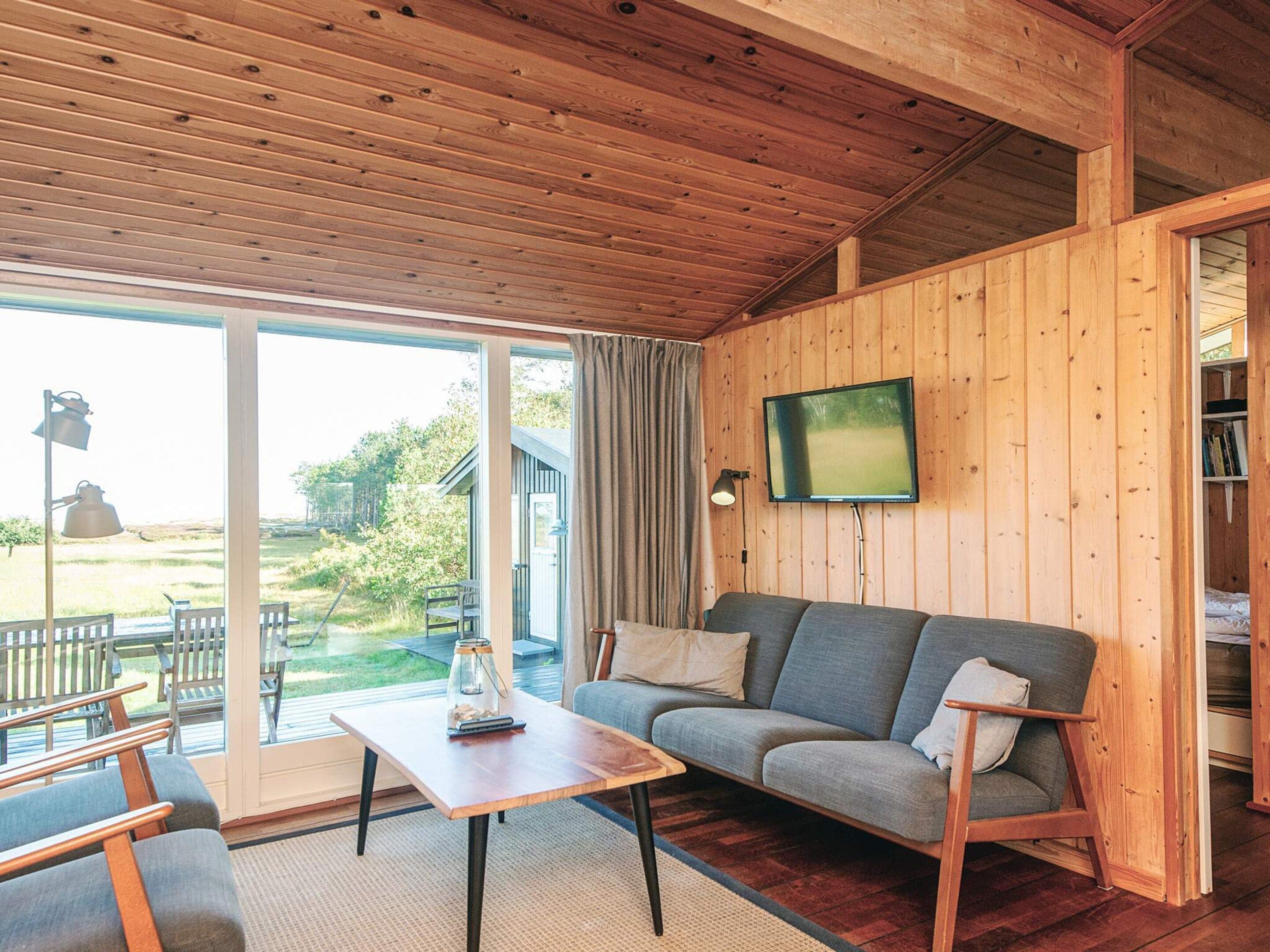 A wooden interior with a sofa, table, and a TV mounted on the wall.