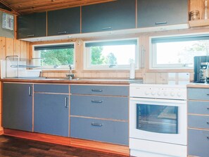A modern kitchen with dark cabinets, a white stove, and a window above the sink. - Elegant Holiday Home in Nordjylland near Sea (Læsø)