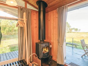 A wood-burning stove in a room with wooden walls and a view of the outdoors. - Elegant Holiday Home in Nordjylland near Sea (Læsø)
