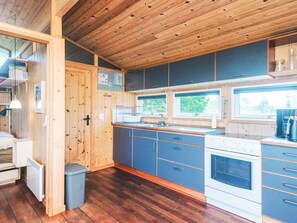 A compact kitchen with wooden cabinetry, a built-in oven, and a window providing natural light. - Elegant Holiday Home in Nordjylland near Sea (Læsø)