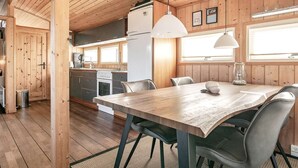 Puinen mökki, jonka sisätiloissa on ruokailutila, keittiö ja suuri ikkuna.