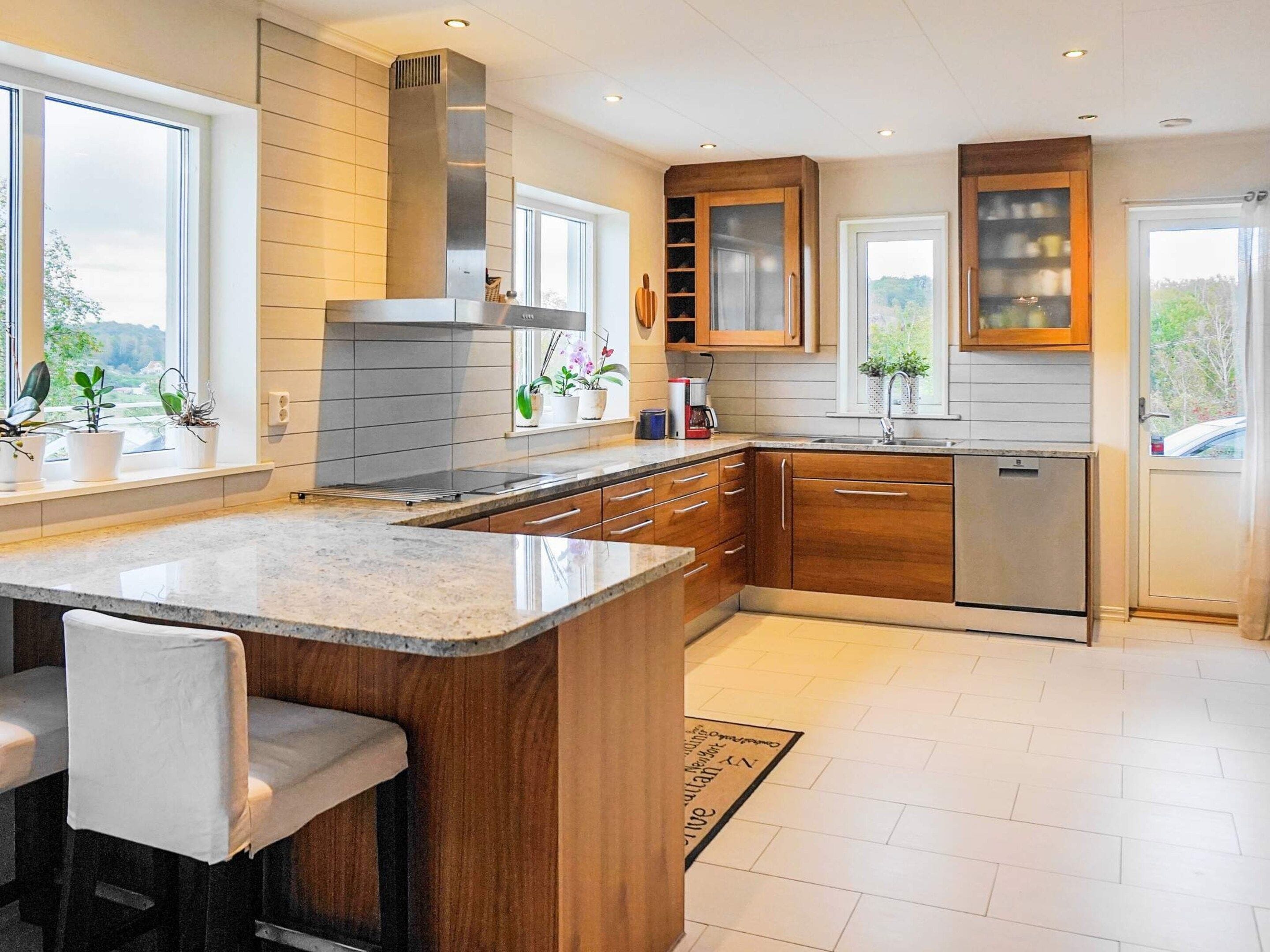 A modern kitchen with a central island, wooden cabinets, and a stainless steel range hood.