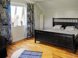A bedroom with a bed, a window with curtains, a chair, and a round table. - Holiday Home in KlÃ¶vedal (Klovedal)