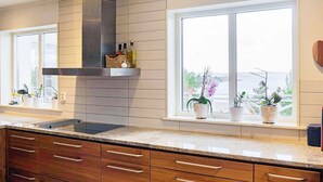 Une cuisine moderne avec des meubles en bois, une hotte en acier inoxydable et une fenêtre agrémentée de plantes en pot.
