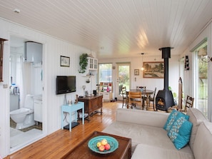 A cozy living room with a fireplace, a television, and a dining area with a table and chairs. - Garden-view Holiday Home in Svebølle With Terrace (Eskebjerg)