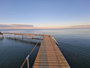 A wooden pier extending into calm water with a clear sky above.