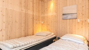 Ein Zimmer mit zwei Betten, Holzwänden und einem Bild an der Wand.