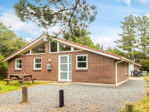 A brick building with a pitched roof, a front door, and a picnic table outside. - 8 Person Holiday Home in Blavand (Blavand)