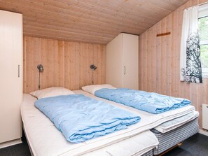 Une petite chambre agréable et chaleureuse, avec deux lits simples, des murs en bois et une fenêtre donnant sur un beau paysage.