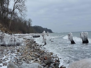 A rocky shoreline with ice formations extending into the water.