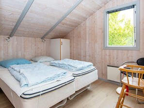Une chambre avec deux lits, une armoire en bois, une chaise et une fenêtre donnant sur un paysage verdoyant.