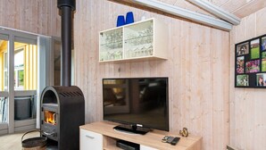 A cozy room with a wood-burning stove, a TV, and a cabinet with glassware.