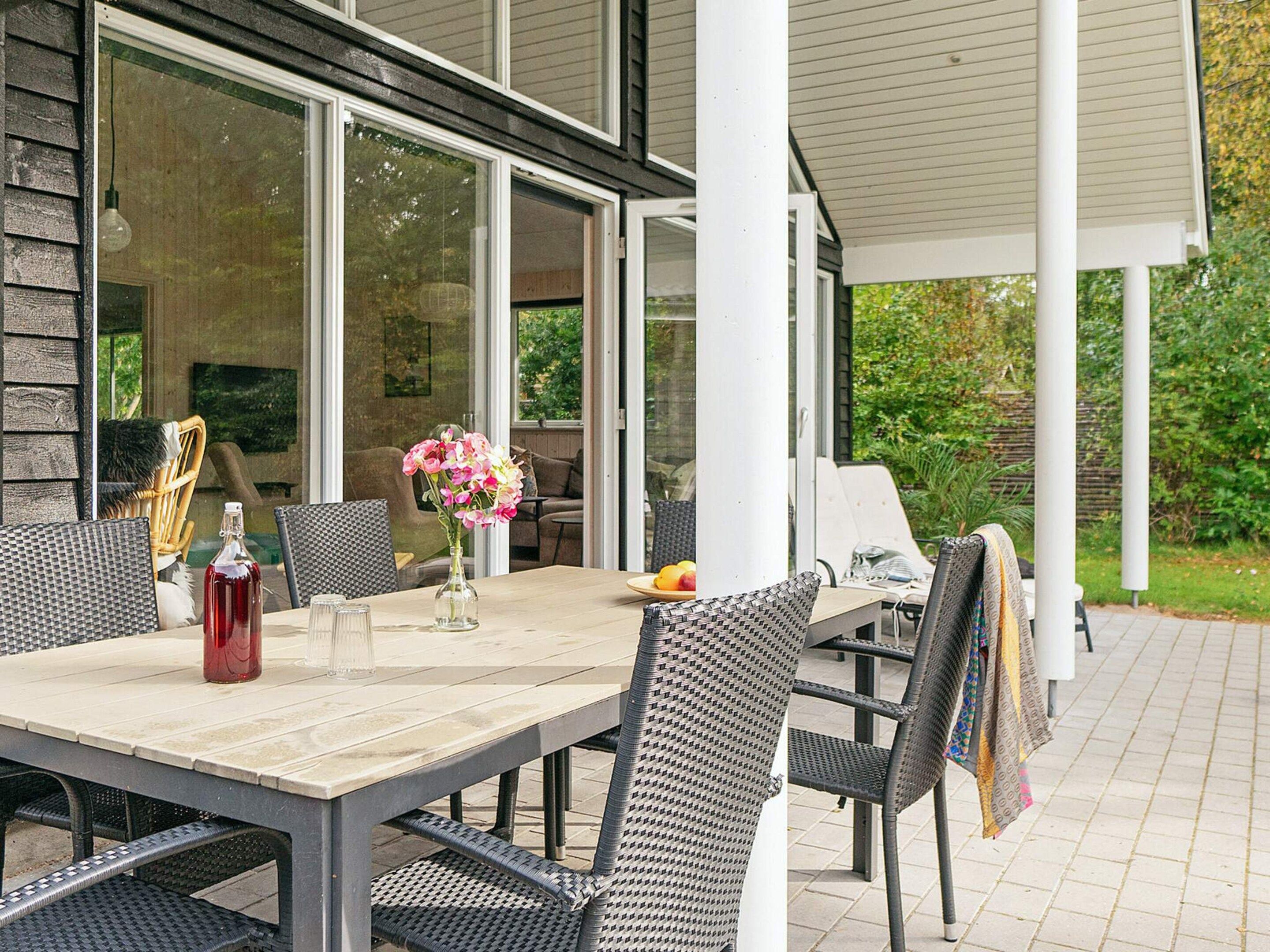 An outdoor patio with a table, chairs, and a bottle of red wine.
