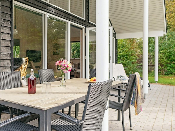 An outdoor patio with a table, chairs, and a bottle of red wine.