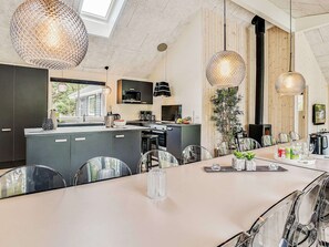 A modern kitchen with dark cabinets, a large island, and hanging pendant lights.