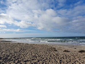 A beach with footprints, waves, and a cloudy sky. - 5 Star Holiday Home in Frederiksvaerk (Frederiksvaerk)