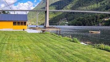 A suspension bridge over a river, a grassy area, and a yellow building.