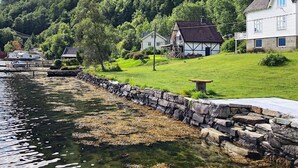 Ein Küstdorf mit traditionellen weißen Häusern, einer Steinmauer und einem Steg mit Booten.