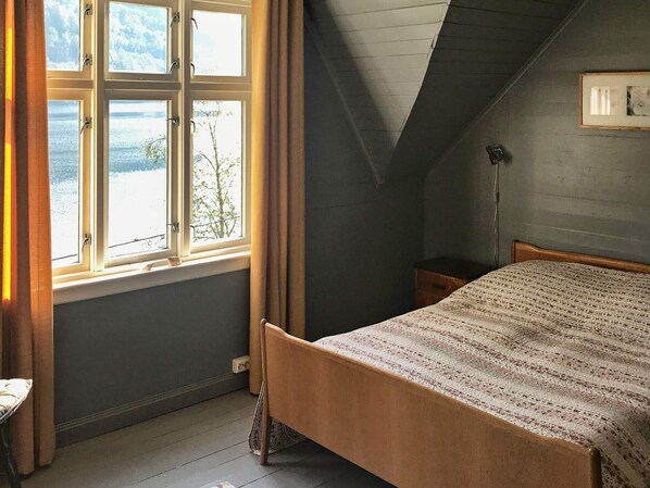 A bedroom with a bed, a window with curtains, a bedside table, and a lamp. - 6 Person Holiday Home in Oystese (Kvam)