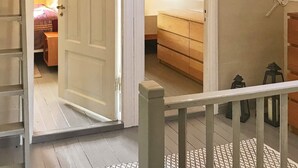 Eine Treppe führt zu einem Schlafzimmer mit einem Bett, einem Schminktisch und einem Nachttisch.