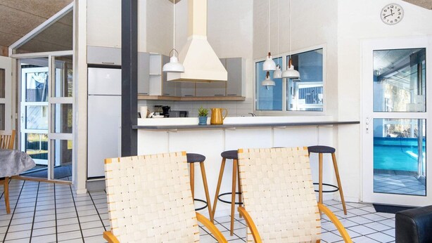 Una cocina moderna con armarios blancos, un ventanal grande y un comedor con sillas de mimbre.