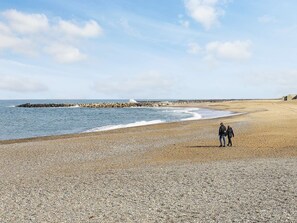 A pebbled beach with a rocky breakwater in the distance.