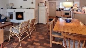Una sala de estar acogedora con chimenea, un comedor con mesa y sillas de madera, y una cocina con electrodomésticos modernos.