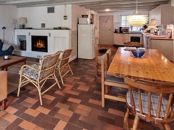 A cozy living room with a fireplace, a dining area with a wooden table and chairs, and a kitchen with modern appliances.