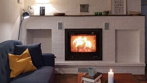 Una sala de estar con chimenea, un sofá, una mesa de centro y una lámpara.