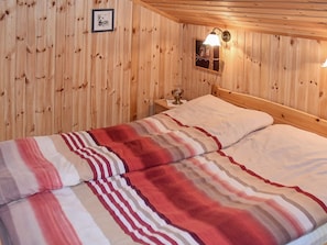 Una stanza con pannelli in legno, un letto, un comodino, una lampada a parete e un quadro incorniciato.