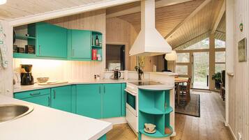 A kitchen with teal cabinets, a white countertop, and a large window.