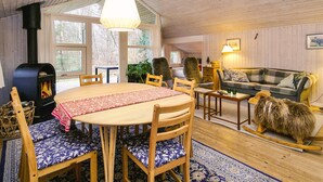 Interior acolhedor de uma cabana com uma mesa de jantar de madeira, cadeiras, um sofá e uma lareira.
