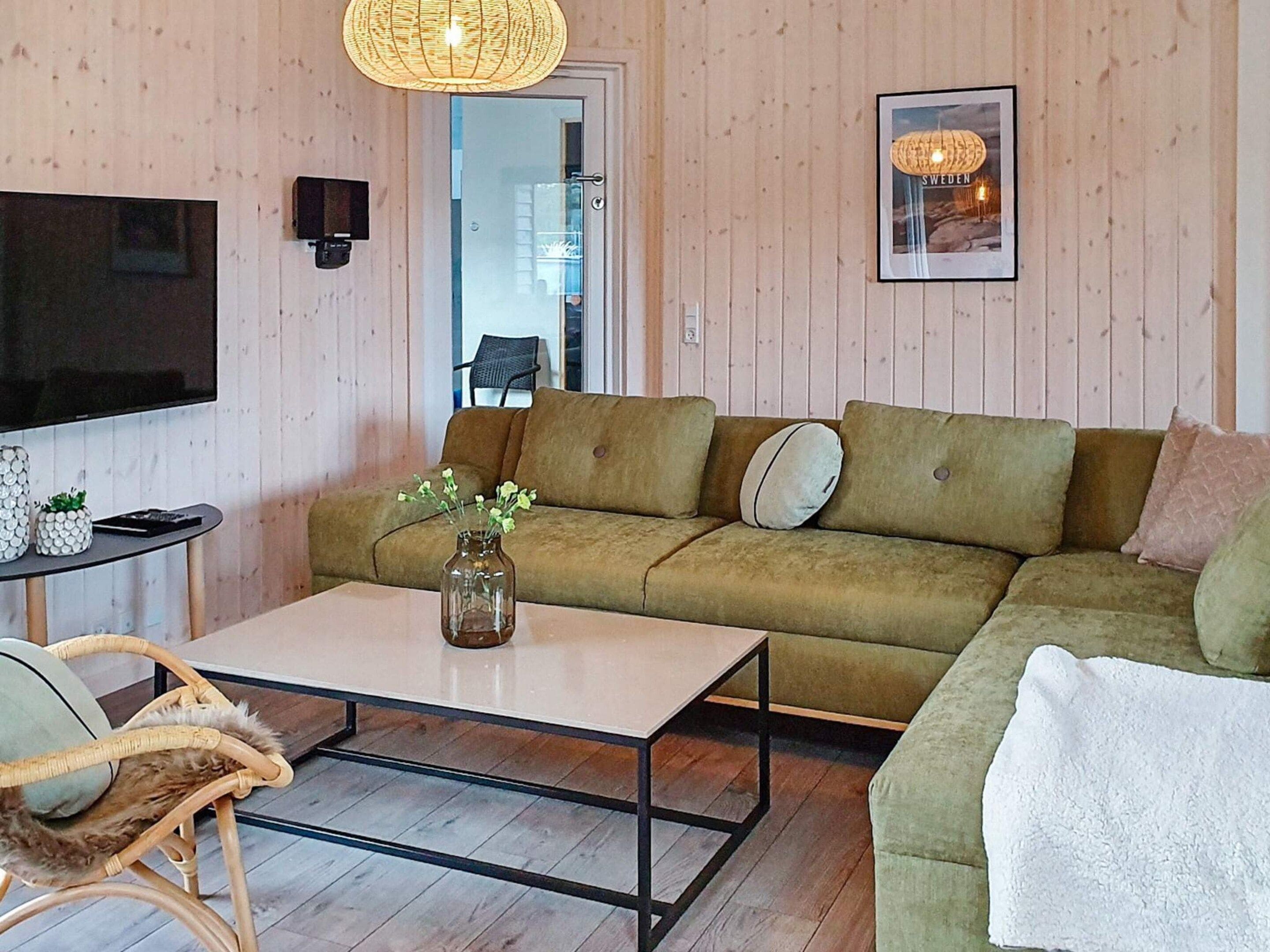 Een woonkamer met een bank, een salontafel, een televisie en een lijst met een foto aan de muur.