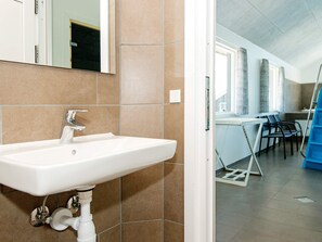 A bathroom with a white sink, a mirror, and brown tiles. - 5 Star Holiday Home in Norre Nebel (Norre Nebel)