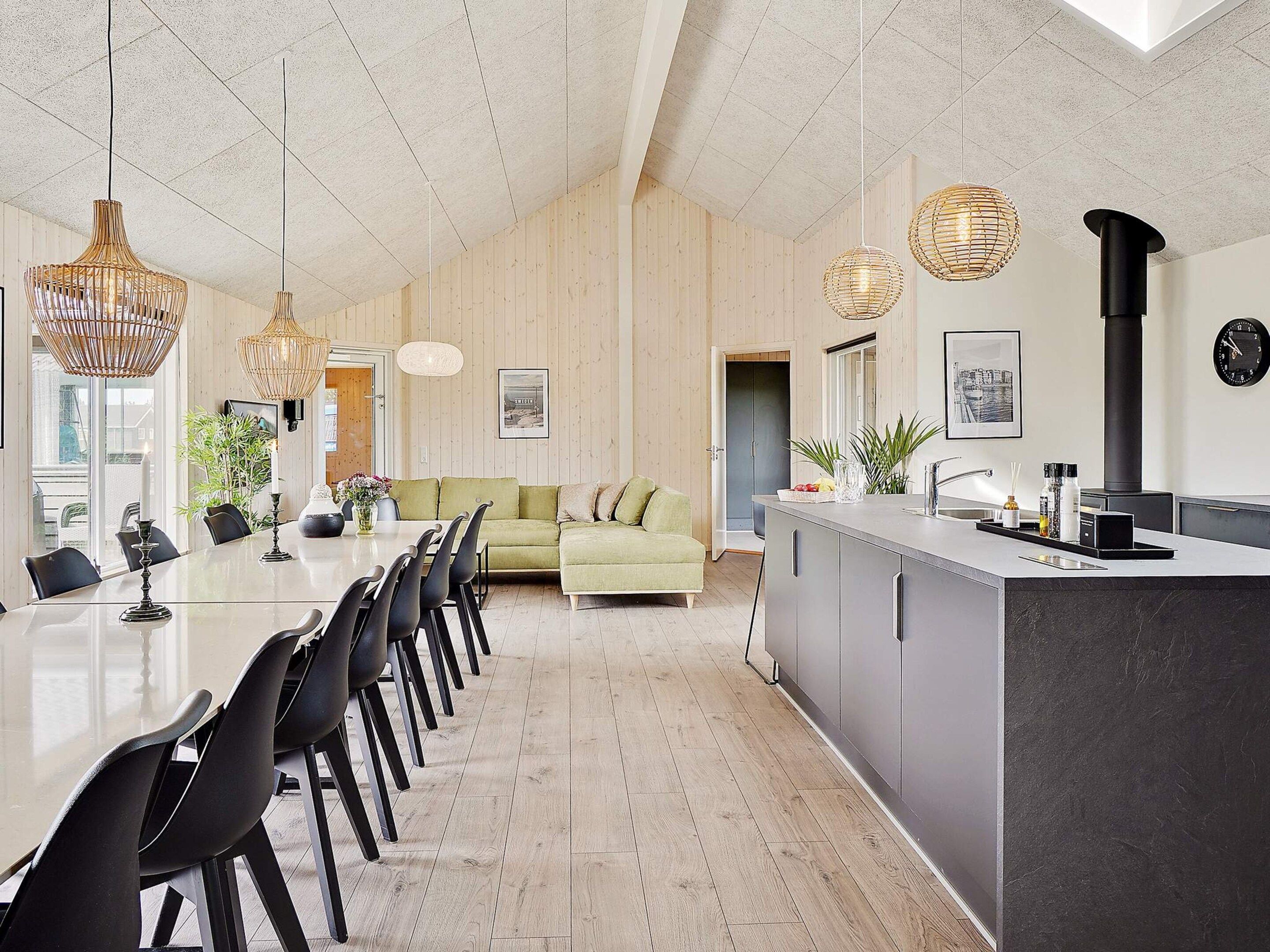 A modern kitchen with a central island, pendant lighting, and a visible clock on the wall.
