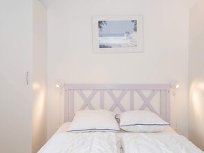 Cozy retreat with a centered bed, geometric headboard, and framed artwork.