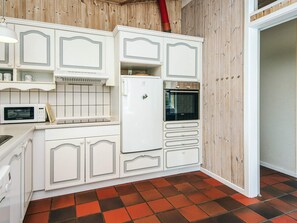 A compact kitchen with white cabinetry, a microwave, a refrigerator, and an oven. - 8 Person Holiday Home in Ebeltoft (Ebeltoft)