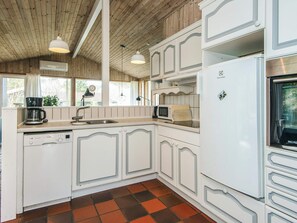 A compact kitchen with white cabinetry, a built-in dishwasher, a microwave, and a refrigerator. - 8 Person Holiday Home in Ebeltoft (Ebeltoft)
