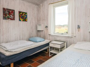 A room with two beds, a window with a view of the countryside, and two wall-mounted lamps. - 8 Person Holiday Home in Ebeltoft (Ebeltoft)
