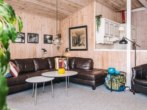 A cozy living room with a brown leather sofa, a round coffee table, and a white cabinet with a plant on top. - 8 Person Holiday Home in Ebeltoft (Ebeltoft)