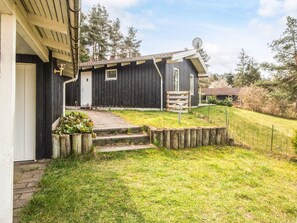 A black wooden house with a satellite dish, a small porch, and a grassy yard. - 8 Person Holiday Home in Ebeltoft (Ebeltoft)
