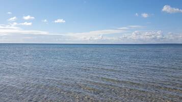 Visão ampla de um mar tranquilo com ondas suaves, céu limpo e horizonte distante.