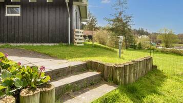 A house with a dark exterior, a satellite dish, a wooden fence, and a grassy yard.