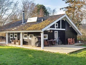 A house with a covered patio, outdoor seating, a barbecue, and a bicycle. - 4 Person Holiday Home in Praesto (Praesto)