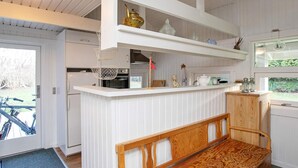 A kitchen with white cabinetry, a wooden bench, and a hanging light fixture. - 4 Person Holiday Home in Praesto (Praesto)