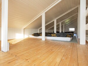 A high-ceilinged attic bedroom with a wooden floor, a bed with a patterned bedspread, and a skylight. - 4 Person Holiday Home in Praesto (Praesto)